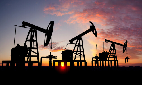 Three Oil Derrick Pumps at Sunset